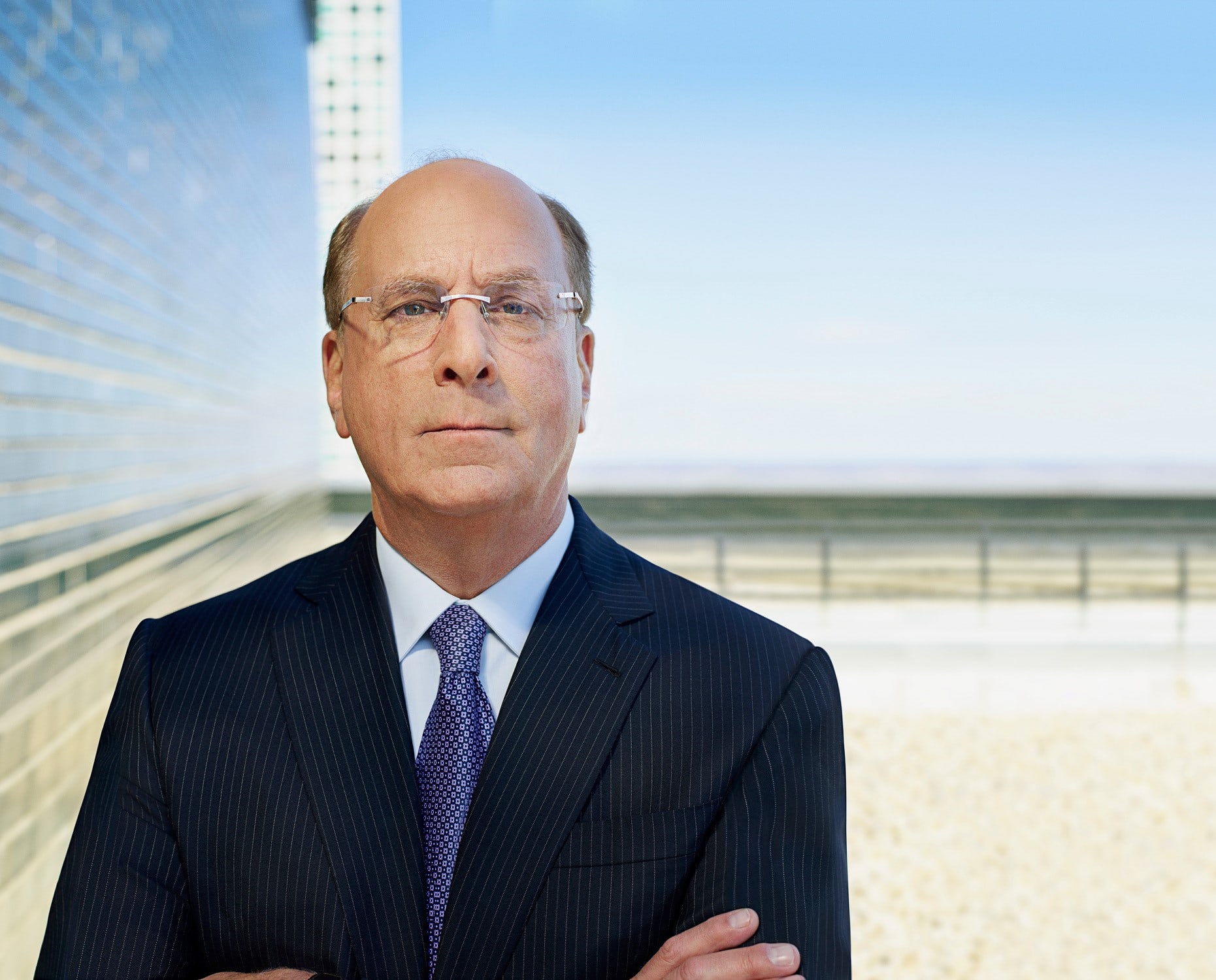 Larry Fink smiling and wearing a more informal grey suit without a tie.